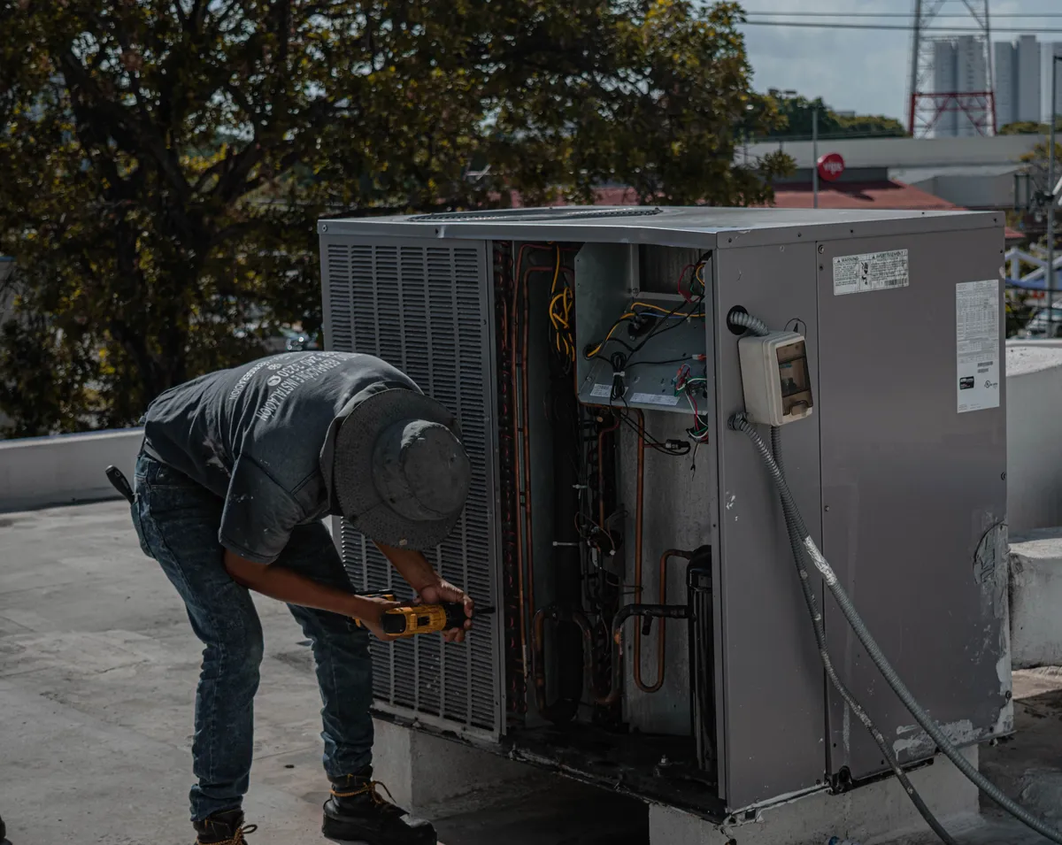 Technician repairing an outdoor rooftop air conditioning unit — illustrative stock photo, not an actual St. George job site